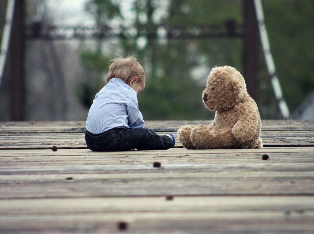 落ち込んでいる男の子と熊のぬいぐるみ