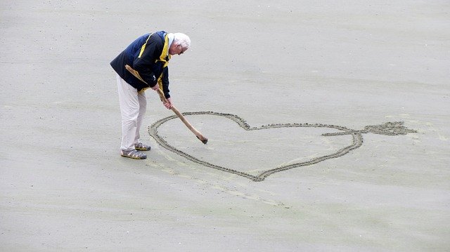 砂浜にハートマークを書くおじさん